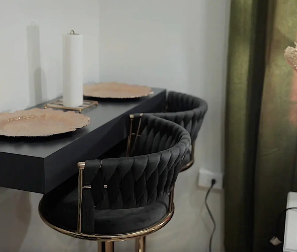 Black velvet bar stools at a dark counter with gold chargers