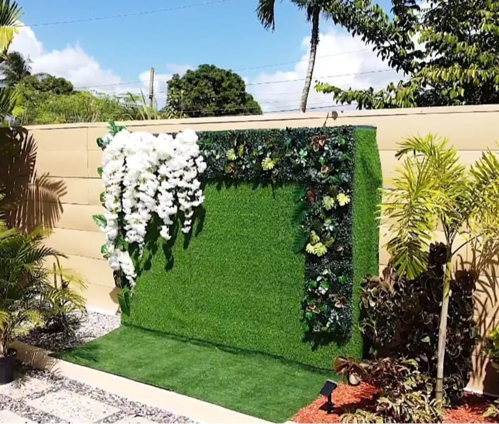 Green photo wall with hanging white flowers under palm trees