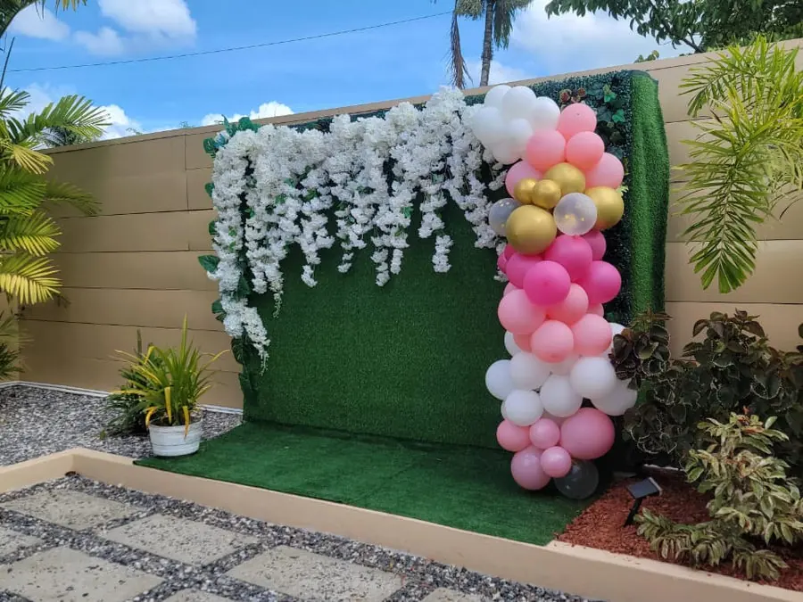 A round table dressed in white with pink napkins and greenery, set on the lawn